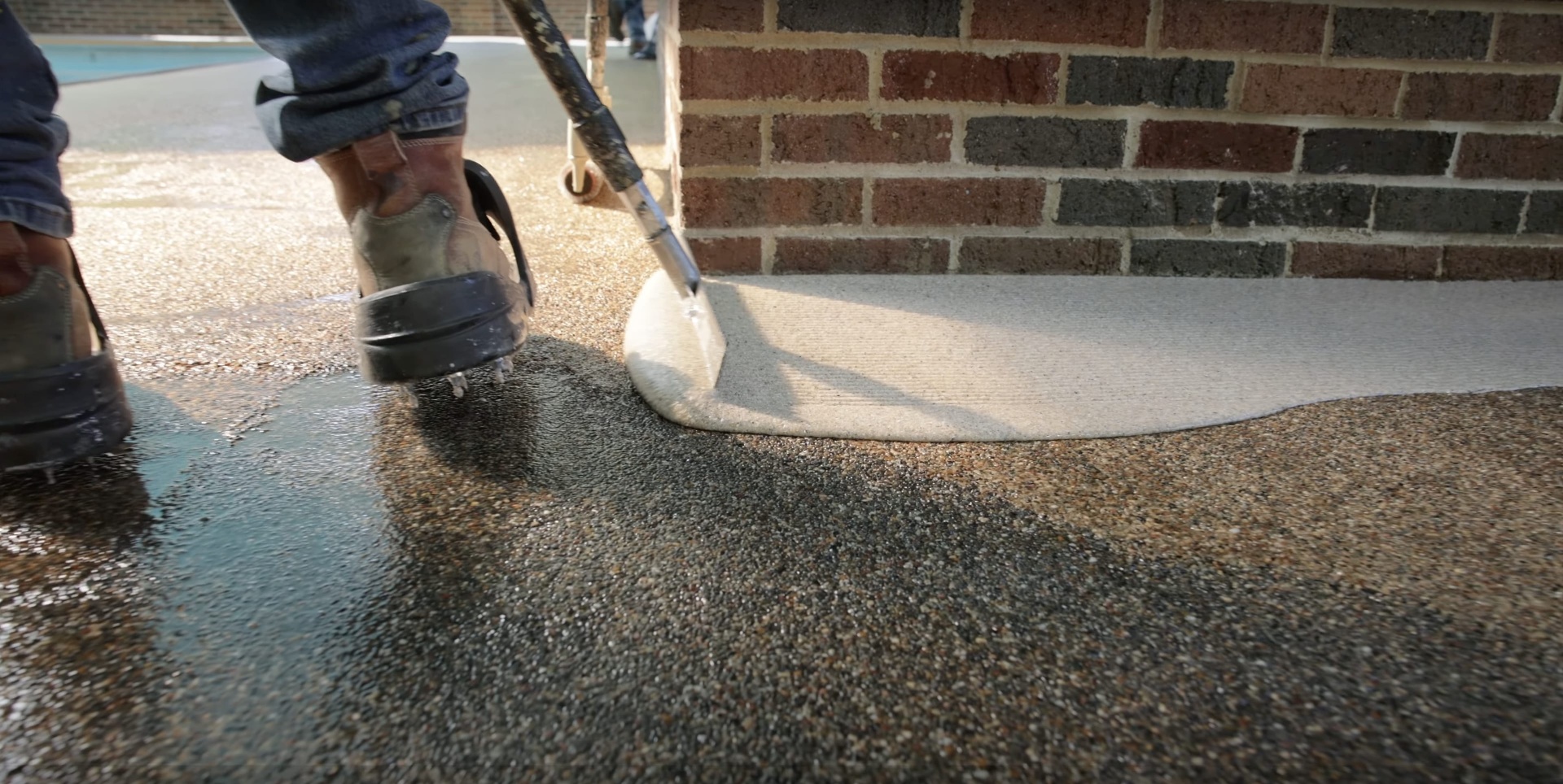 Expert concrete surface finishing and texture work Professional concrete finishing with specialized tools on exposed aggregate surface